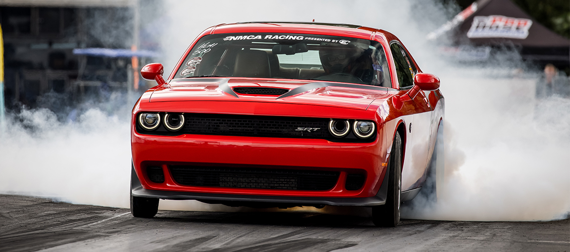 Dodge Challenger doing a burnout on a drag strip