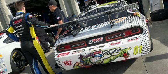 2 men standing next to a race car